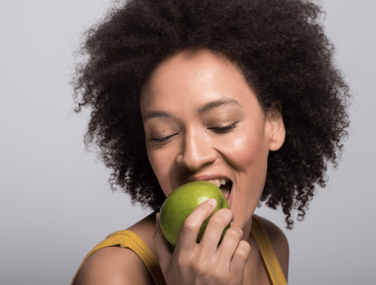 woman-holding-taking-bite-of-green-apple